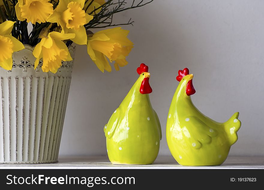 Two Easter roosters next to daffodils. Two Easter roosters next to daffodils