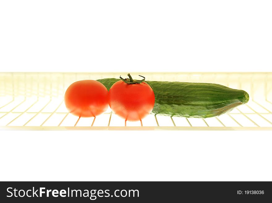 Rack with tomato and cucumber in the fridge. Rack with tomato and cucumber in the fridge.