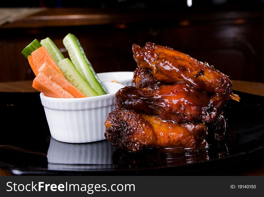 Chicken legs with some vegetables on a black porcelain plate