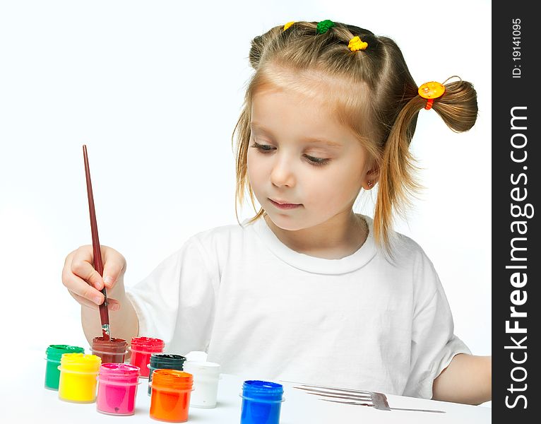 Cute little girl with a brush and paints