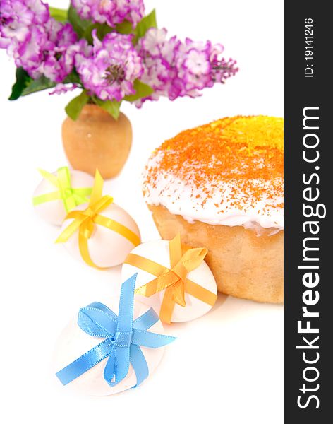 Easter cake and eggs decorated with bows. Vase with a lilac bouquet. Isolated on white