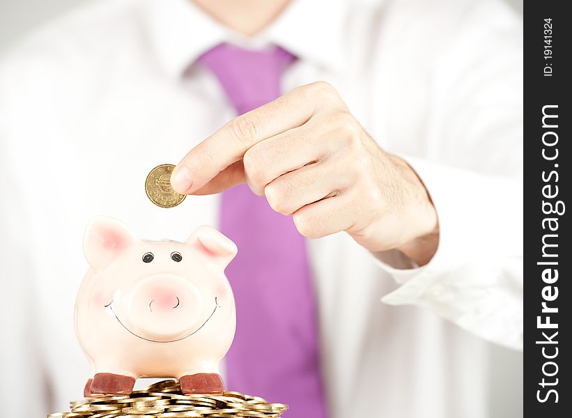 Businessman saving money on a piggy bank