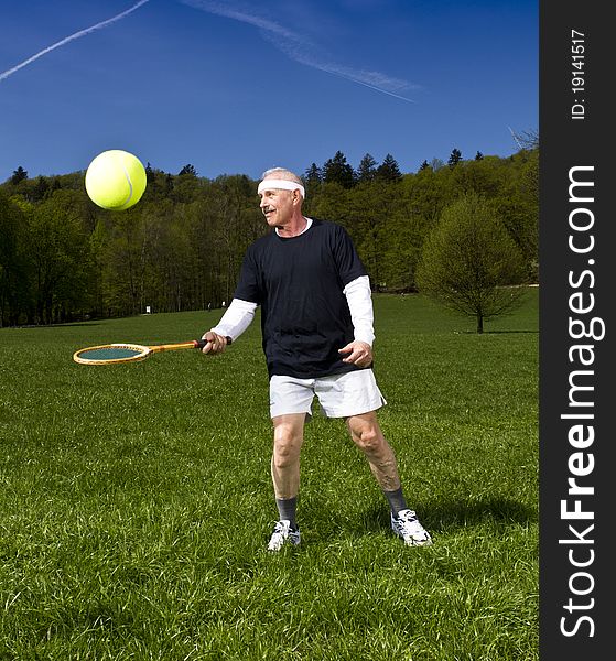 Senior man playing tennis with retro racquet