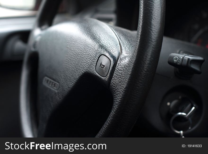 Dark grey teering wheel inside of a car with a horn in it. Dark grey teering wheel inside of a car with a horn in it