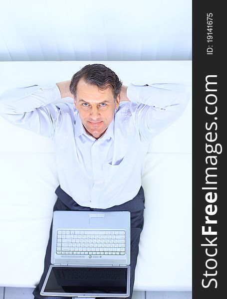 Entrepreneur working from home looking very relaxed in his sofa browsing the web in his laptop computer. Entrepreneur working from home looking very relaxed in his sofa browsing the web in his laptop computer