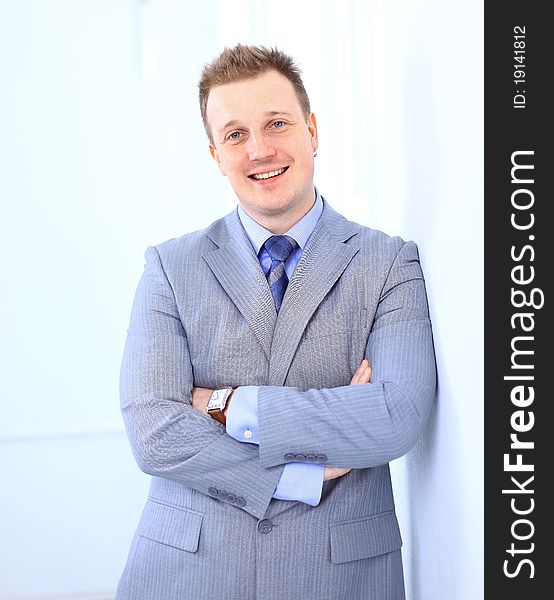 Full length of a handsome business man with hands folded against white background