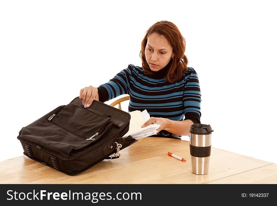 A woman is putting some papers in a bag on the table. A woman is putting some papers in a bag on the table.
