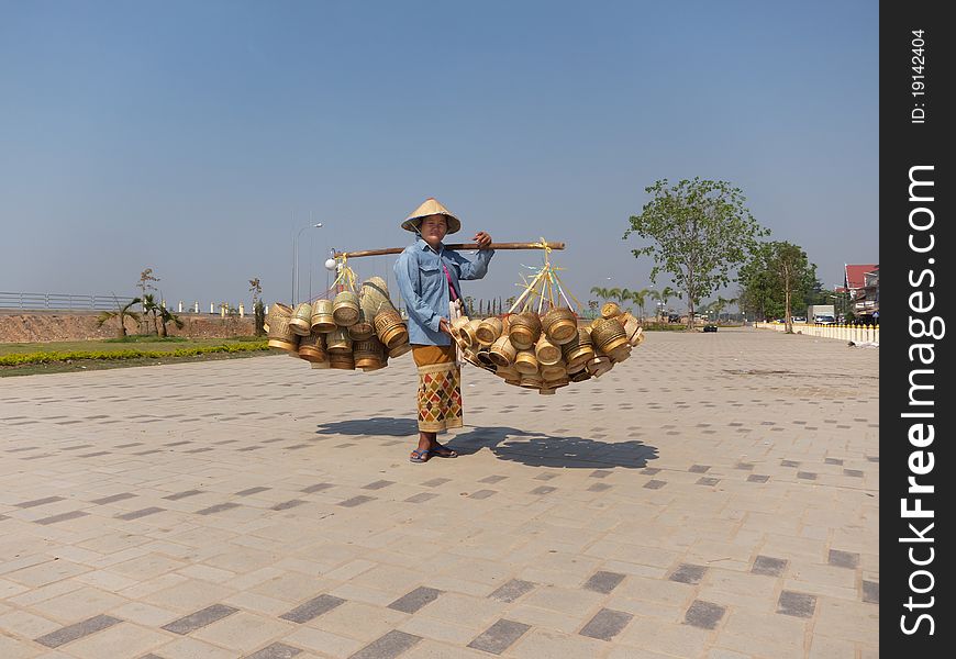 Traditional asian sale on the street, woman with baskets in Laos