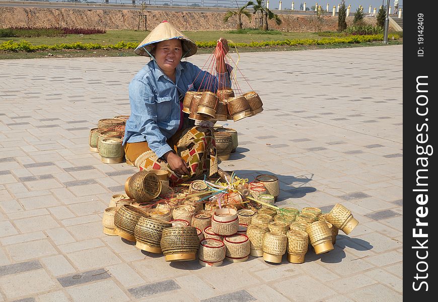 Traditional asian sale on the street, woman with baskets in Laos