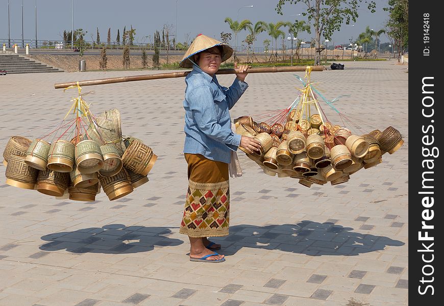 Traditional asian sale on the street, woman with baskets in Laos