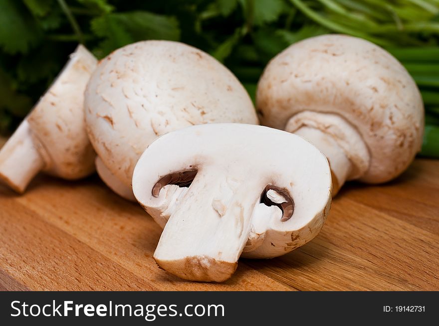 Field mushrooms and greens on chopping board