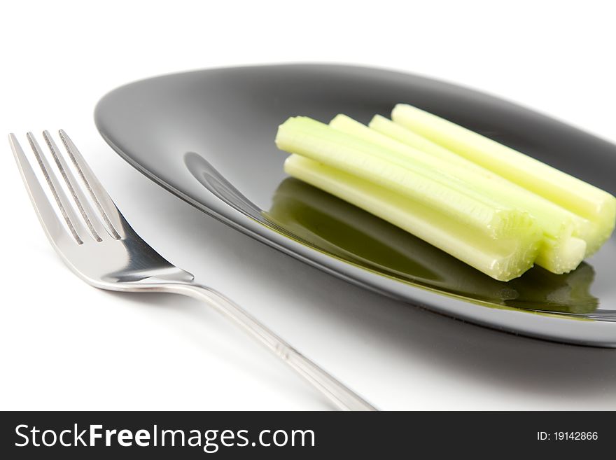 Green celery on black plate with fork. Green celery on black plate with fork