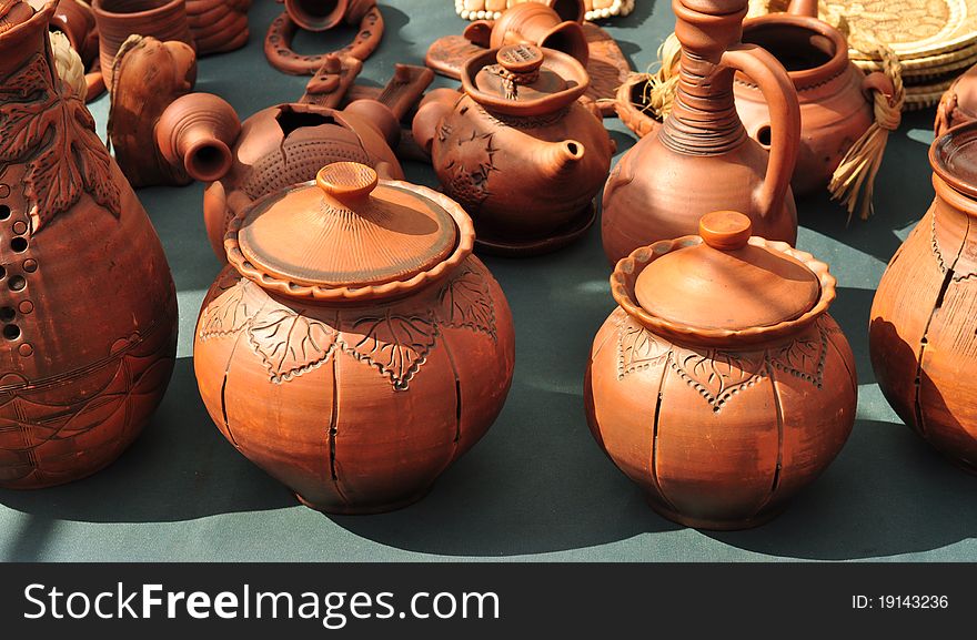 Handwork, tableware made of clay, dishes for food and beverages, brown with a lid, beautiful patterns, stand in the sun outdoors. Handwork, tableware made of clay, dishes for food and beverages, brown with a lid, beautiful patterns, stand in the sun outdoors