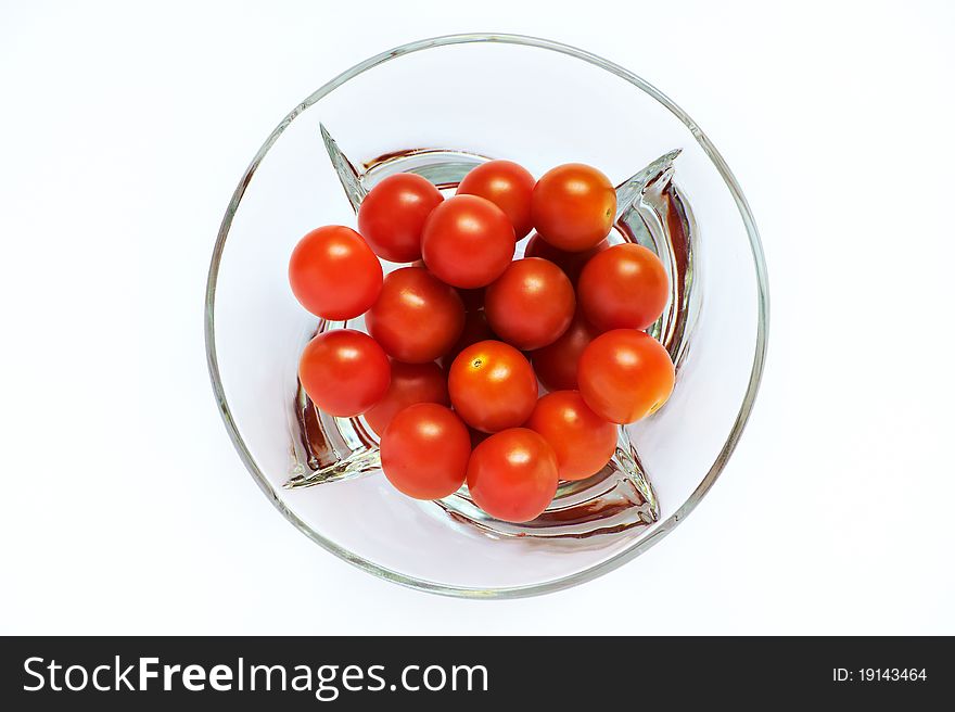 Red tomatoes in a transparent plate on a white background