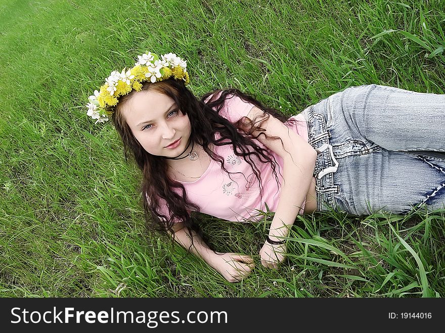 Girl in the spring wreath on the green grass