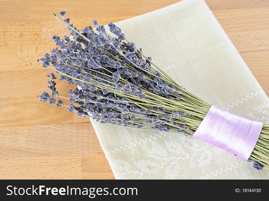 Dried lavender, tied with purple ribbon, with a linen cloth on a wooden table