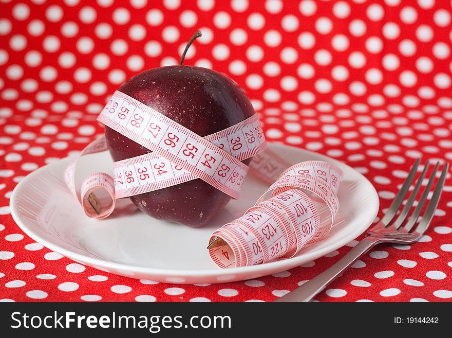 Red Apple And Measuring Tape On A White Plate