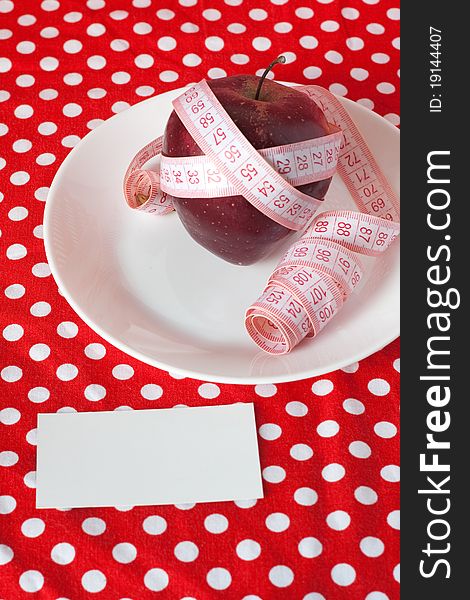 Red apple and measuring tape on a red background