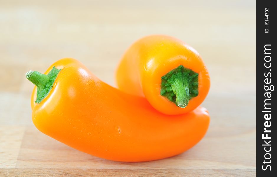 Two sweet orange peppers on a wooden table. Two sweet orange peppers on a wooden table