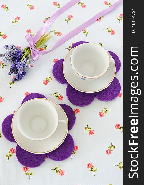 Two cups with a bouquet of muscari on colored tablecloths. Two cups with a bouquet of muscari on colored tablecloths