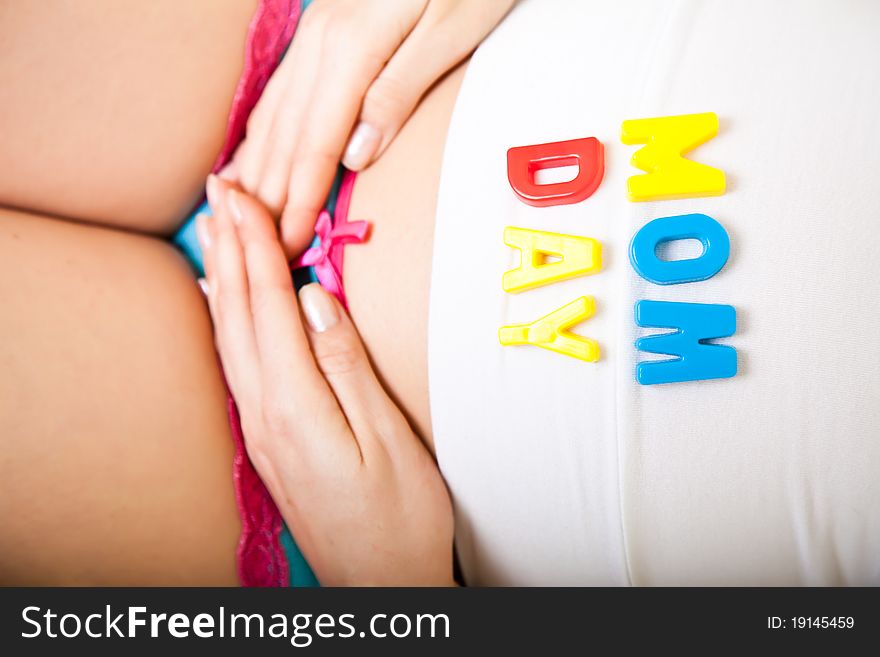 Pregnant woman belly with baby clothes