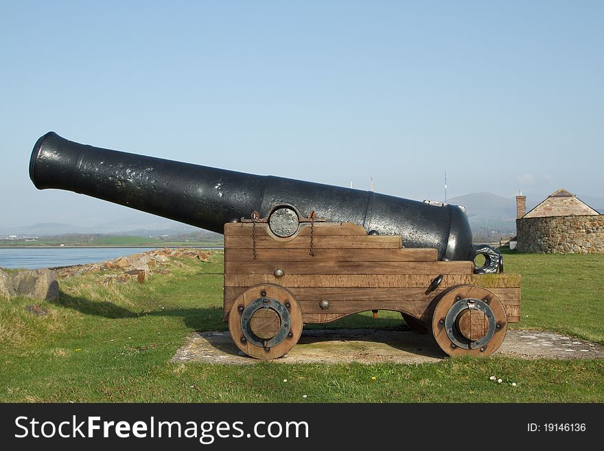 Historic cannon with a black barrel on a wooden trolley with wheels. Historic cannon with a black barrel on a wooden trolley with wheels.