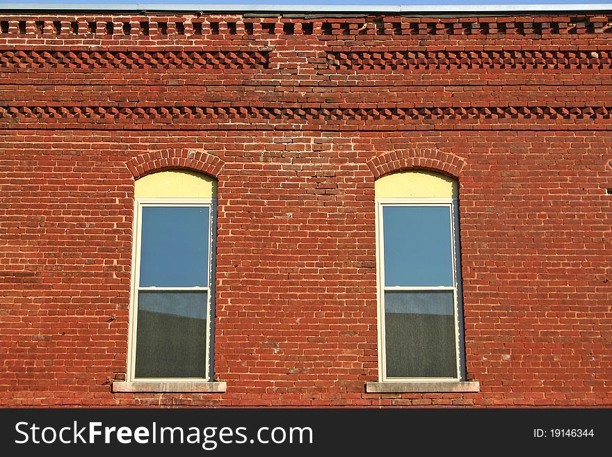 The top of a red brick wall with two windows. The top of a red brick wall with two windows