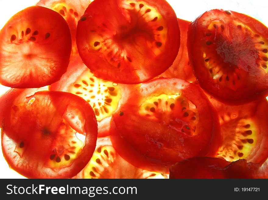 Bright red tomato slices with light shining through causing them to glow. Bright red tomato slices with light shining through causing them to glow.