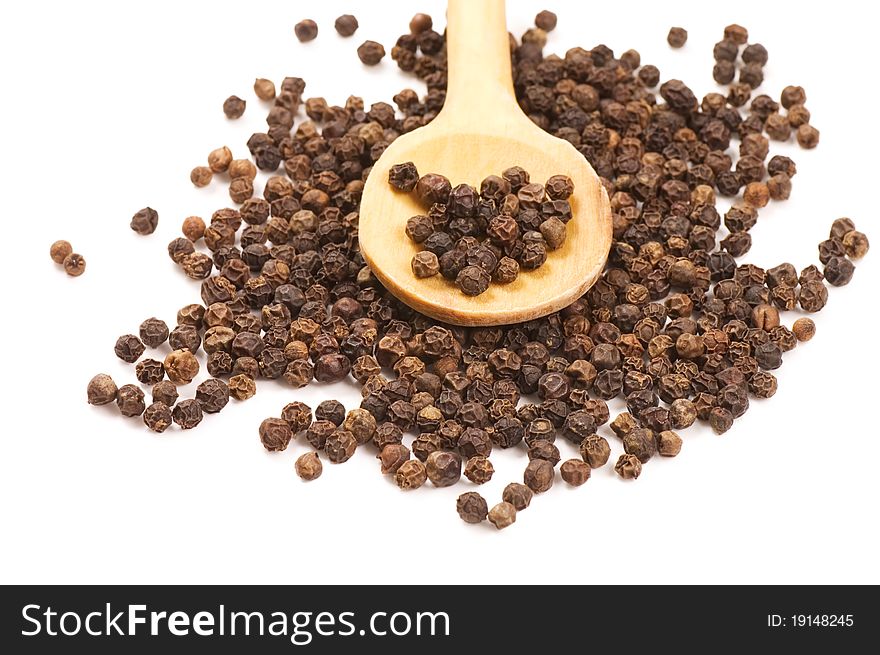 Black Peppercorns on a wooden spoon on white