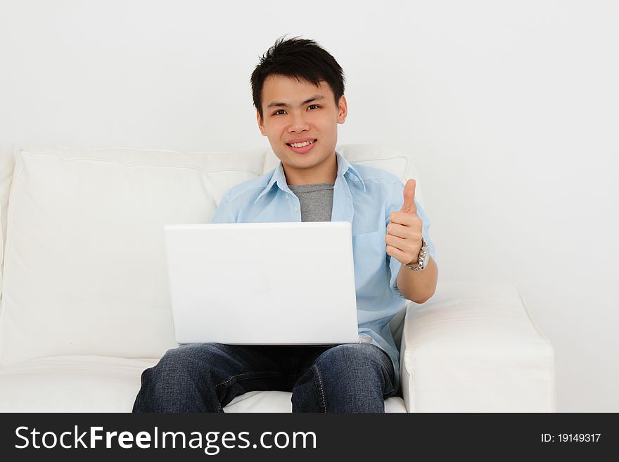 A man with his laptop at home giving thumbs up. A man with his laptop at home giving thumbs up