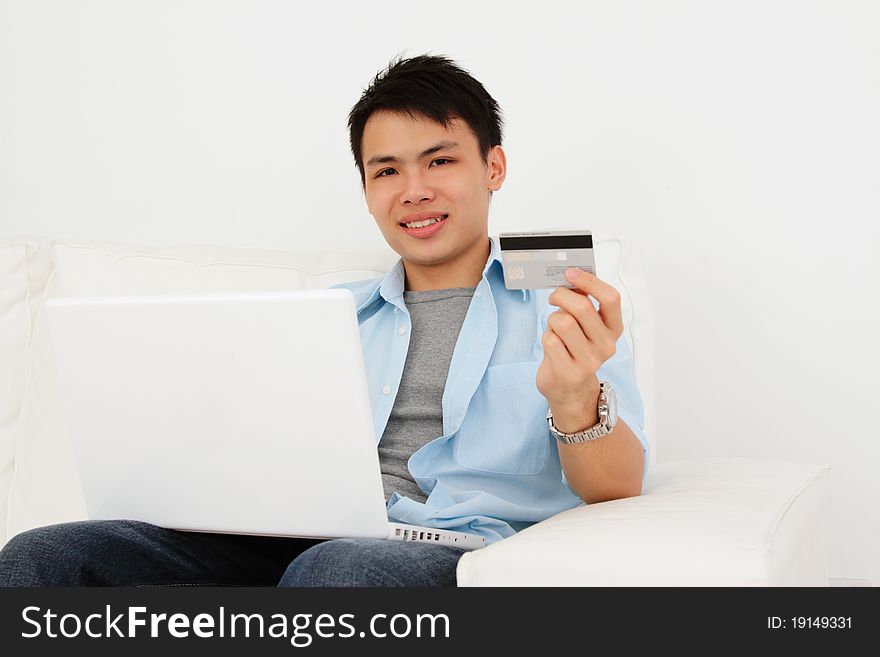 A man doing online shopping at home with his laptop and credit card. A man doing online shopping at home with his laptop and credit card