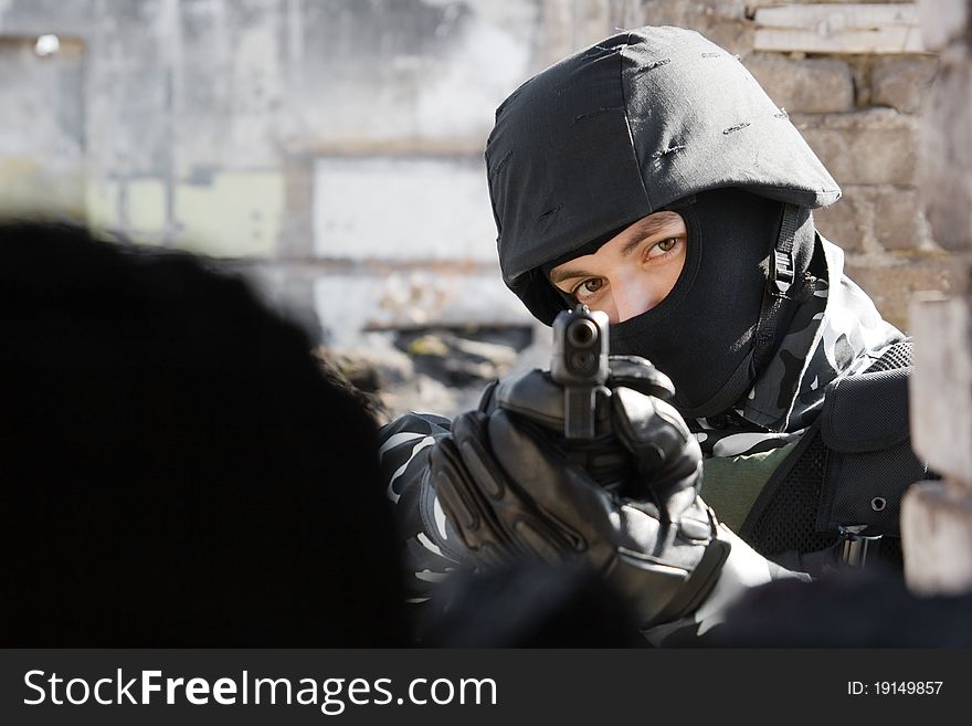 Man in black mask and bulletproof helmet pointing with a 9mm gun in the camera. Man in black mask and bulletproof helmet pointing with a 9mm gun in the camera