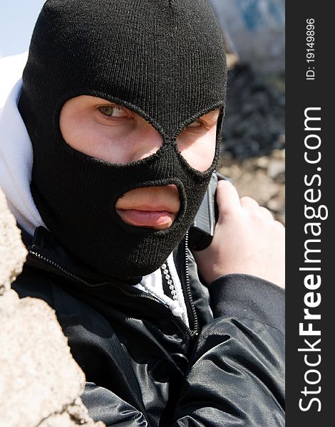 Young adult man in black mask with a 9mm pistol hiding round the corner. Young adult man in black mask with a 9mm pistol hiding round the corner