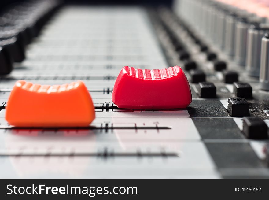 Orange and red slider on a sound mixer with blurry background