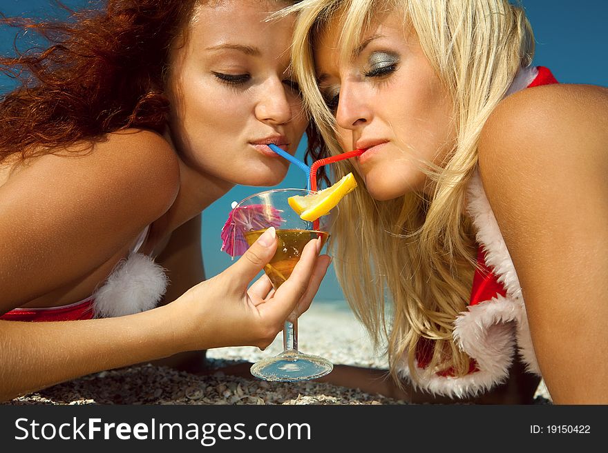 Two pretty girls enjoy martini at the beach. Two pretty girls enjoy martini at the beach