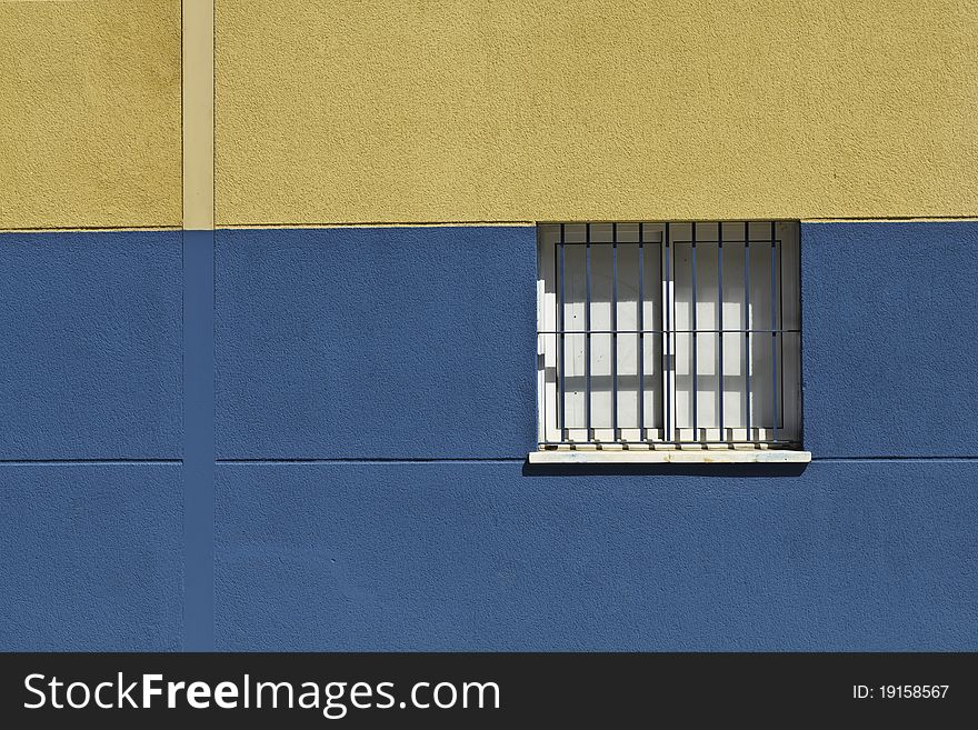 Closed window with bars in a blue and yellow wall in Malaga, Spain. Closed window with bars in a blue and yellow wall in Malaga, Spain