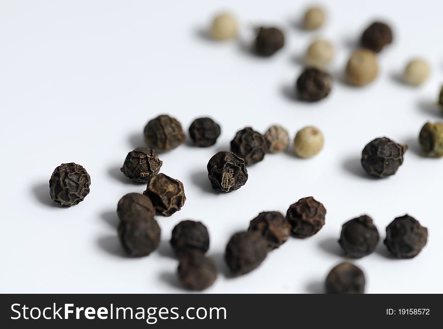 Black and white peppercorns on a white surface. Black and white peppercorns on a white surface