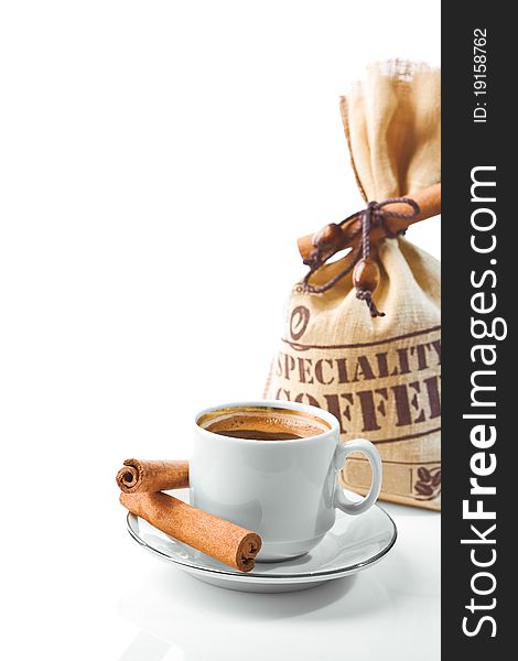 Bright composition of coffee cup and coffee sack with cinnamon stick on white background. Bright composition of coffee cup and coffee sack with cinnamon stick on white background