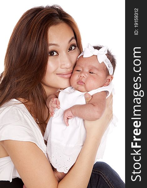 A oriental mother holding her beautiful daughter in her arms putting her lips next to her cheek. A oriental mother holding her beautiful daughter in her arms putting her lips next to her cheek.