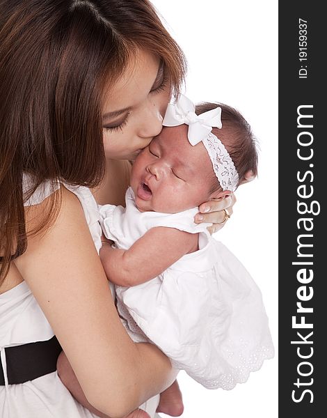 A oriental mother holding her beautiful daughter in her arms kissing her head. A oriental mother holding her beautiful daughter in her arms kissing her head.