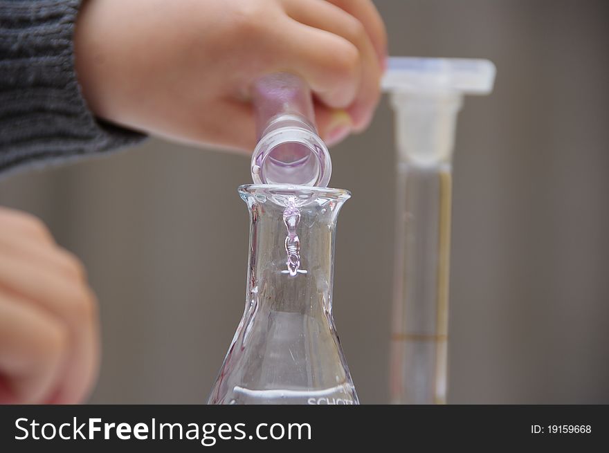 Child's hands are holding tubings to drop the liquid. Child's hands are holding tubings to drop the liquid