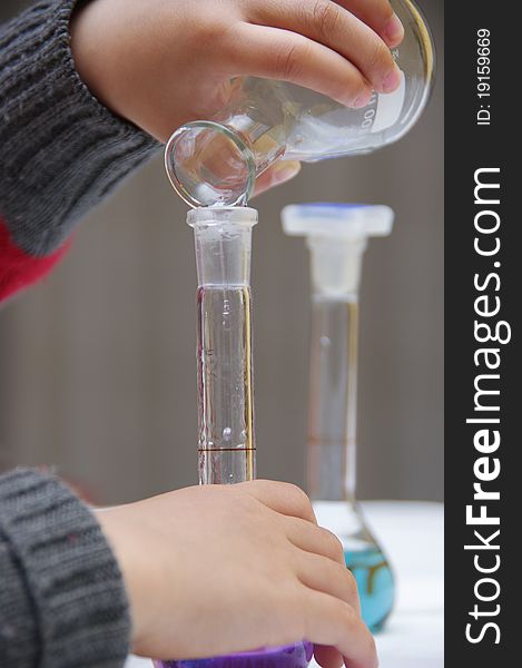 Child's hands are holding a tube to drop the liquid. Child's hands are holding a tube to drop the liquid