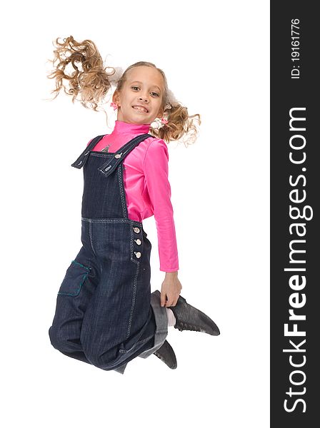 Jumping happy young girl in pink t-shirt and blue overalls