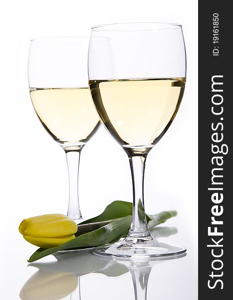 Two glasses of white wine and yellow tulip on a white background. Two glasses of white wine and yellow tulip on a white background
