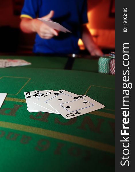 Poker player throwing in cards with a straight flush of clubs in the foreground. Poker player throwing in cards with a straight flush of clubs in the foreground