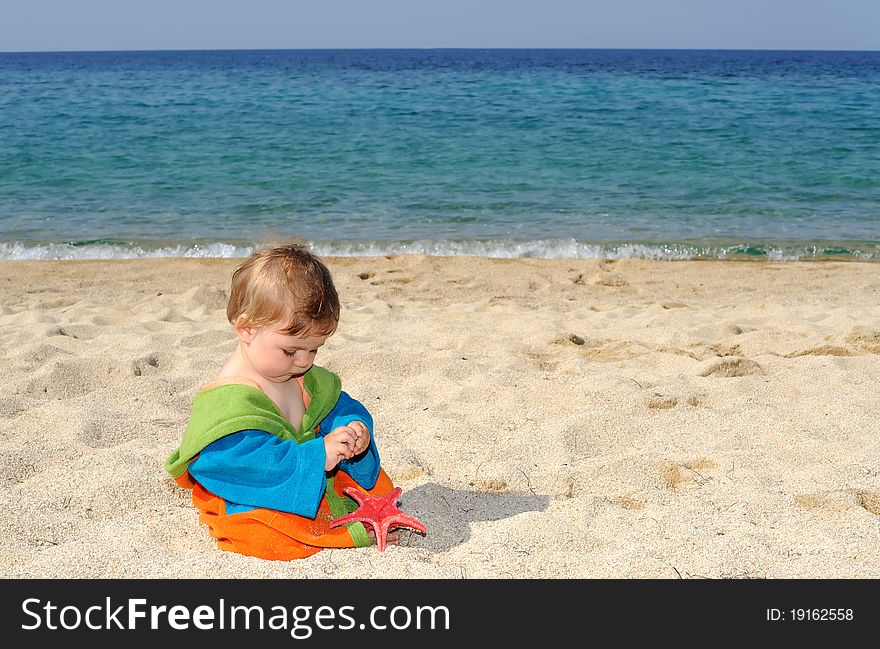 Baby girl playing with red sea stars on the beach