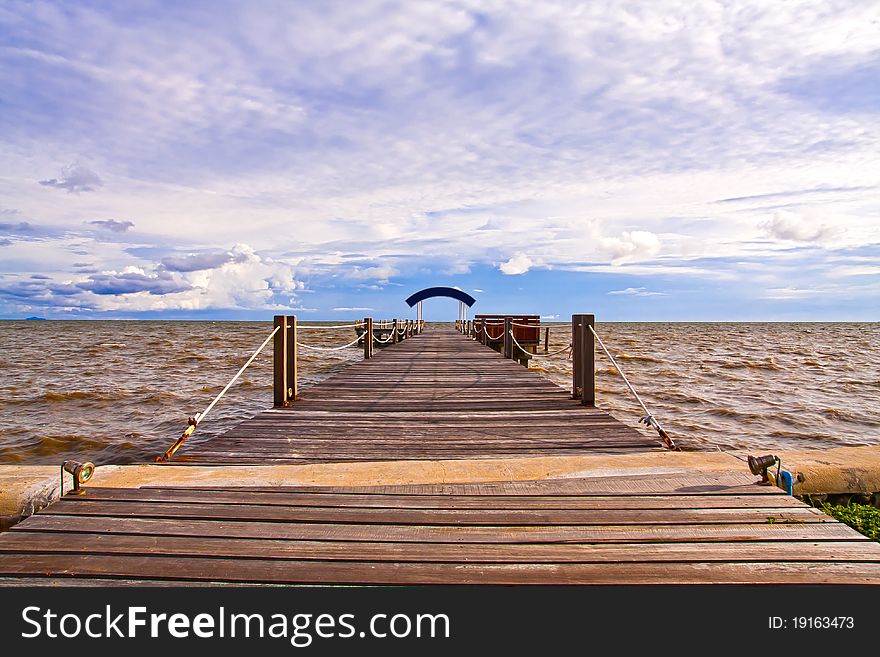 Wooden jetty into the sea with blue sky