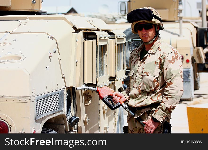 A soldier with helmet and uniform refueling military tactical vehicle outdoor. A soldier with helmet and uniform refueling military tactical vehicle outdoor