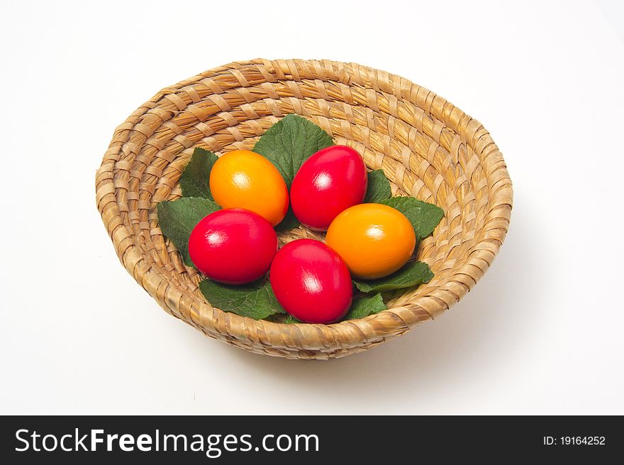 Red and yellow eggs on leaf in basket. Red and yellow eggs on leaf in basket