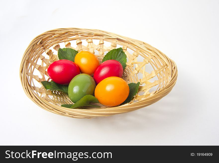 Five colored eggs on leafs in a basket on white background. Five colored eggs on leafs in a basket on white background